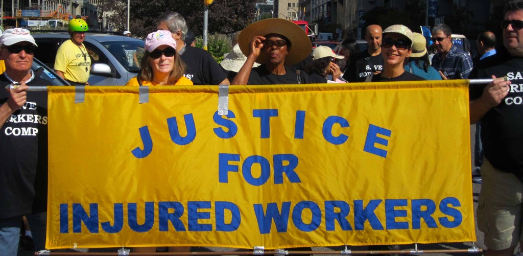 Workers hold Justice for injured workers banner on street